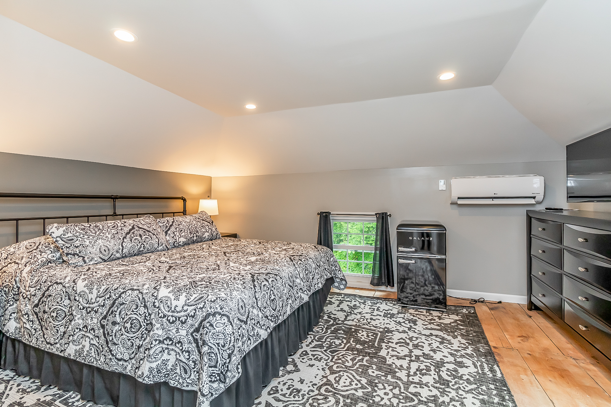 Wide view of the king bedroom with mini fridge and dresser