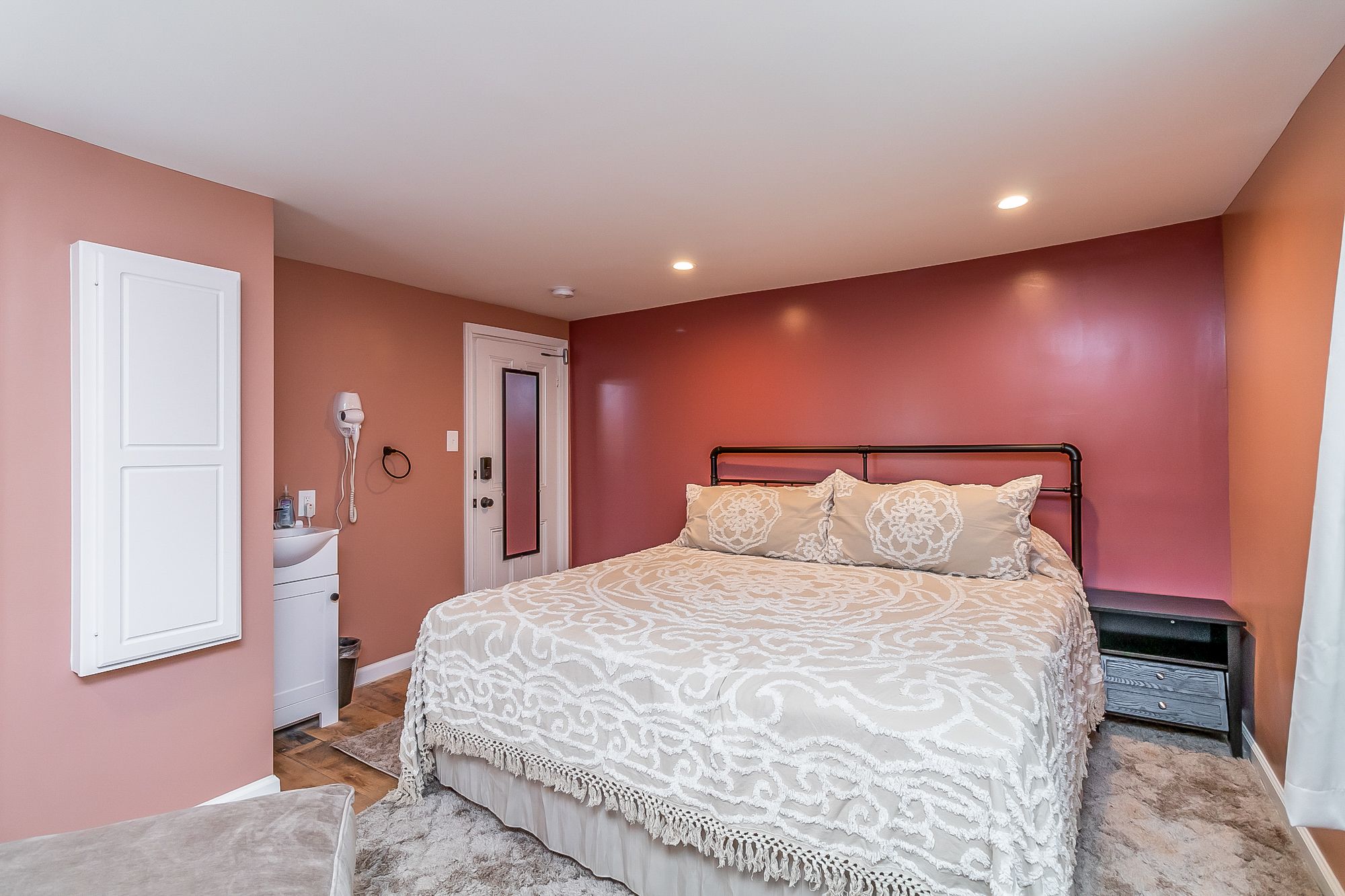 Rose bedroom with iron bed, in-room vanity sink and hair dryer