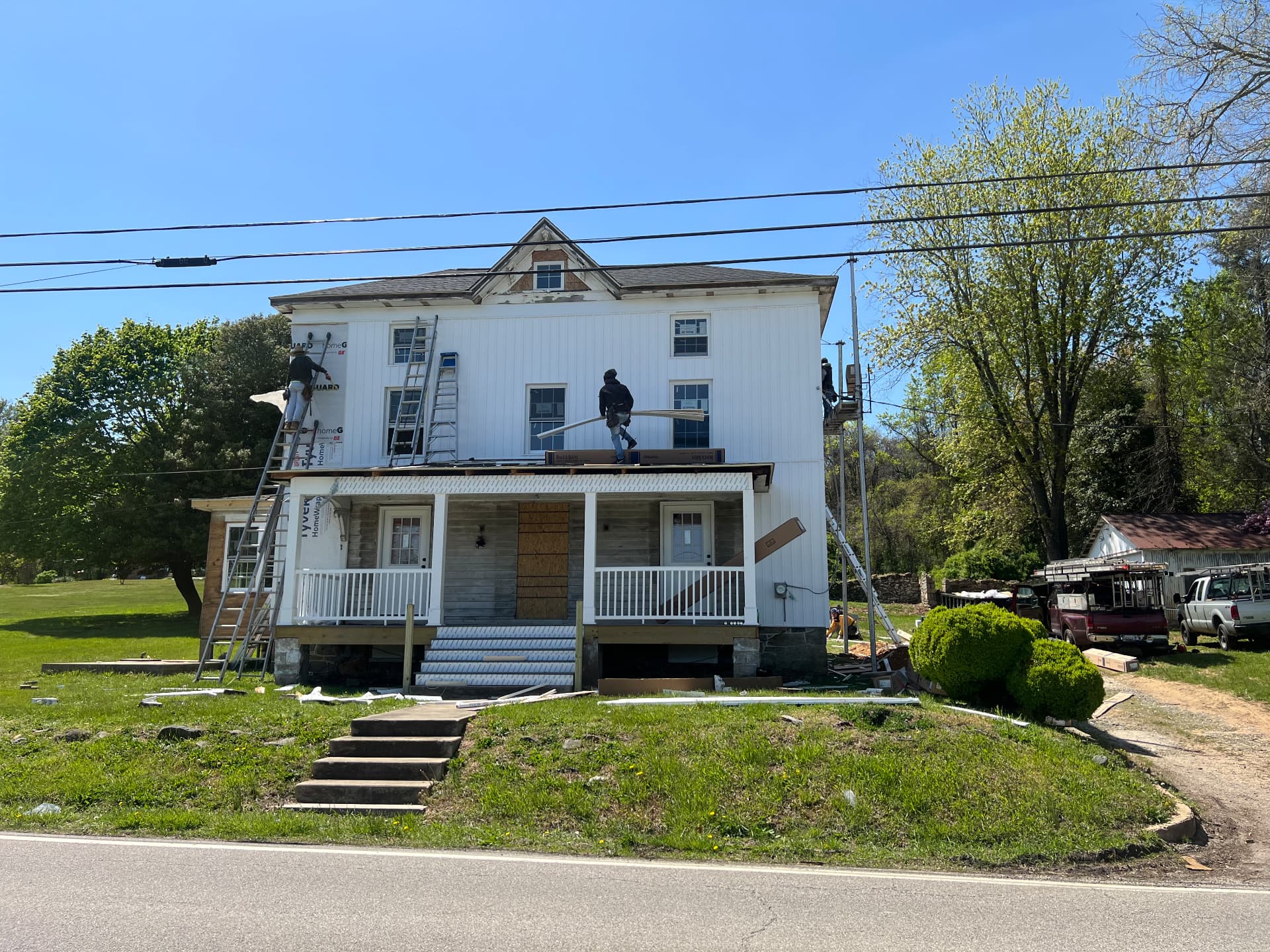 Crew installing new white board-and-batten siding across the front of the house