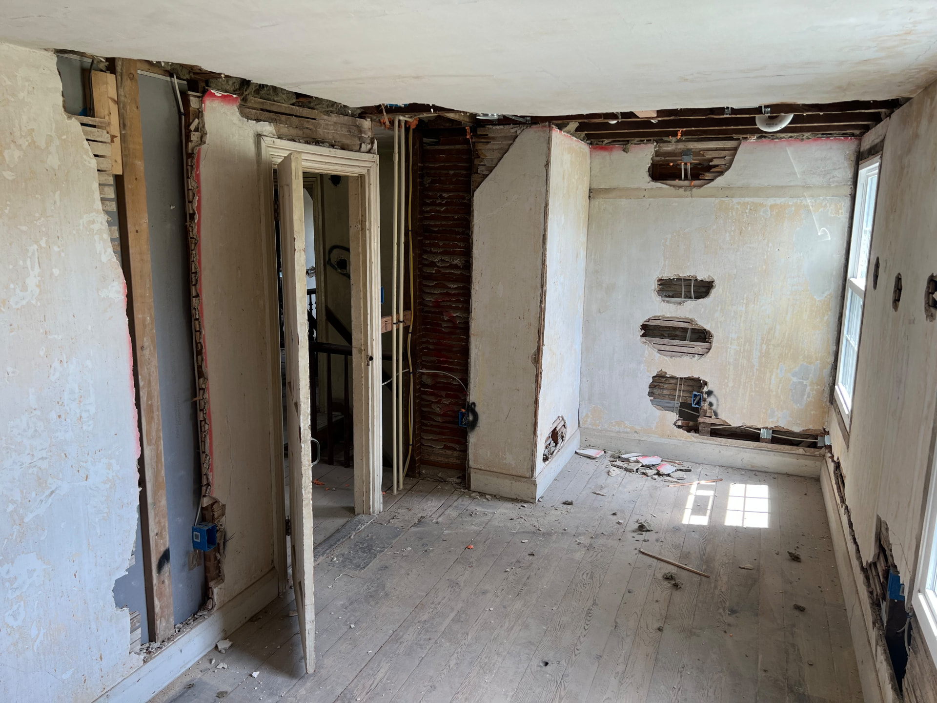Bedroom plaster opened to hand-split lath and the original brick chimney