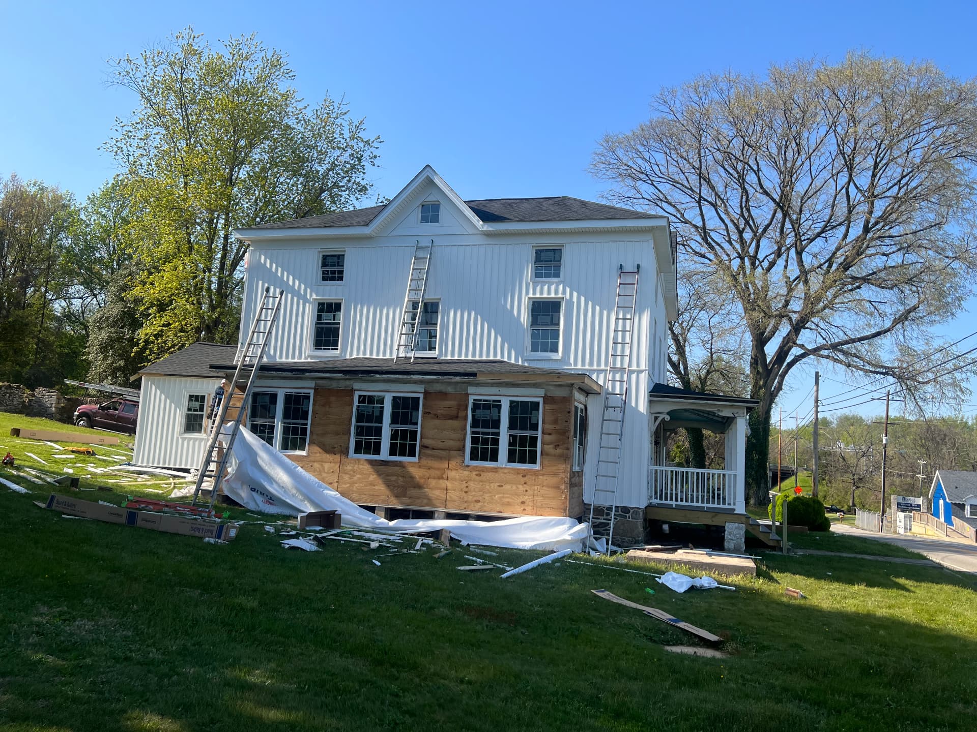 Rear of the house in new white siding with the sunroom sheathed and ready