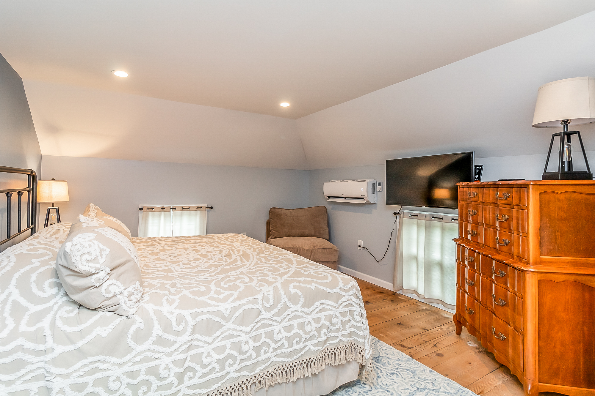 Upstairs bedroom with a queen bed, TV and original wide plank floors