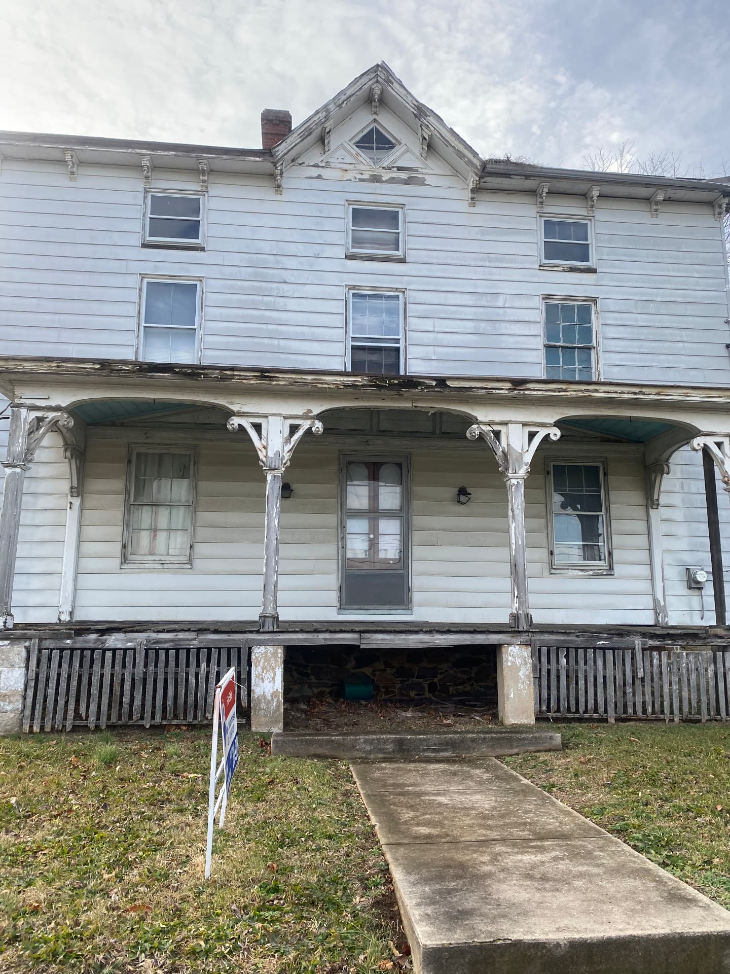 Front porch before restoration with rotted decking and weathered Victorian brackets