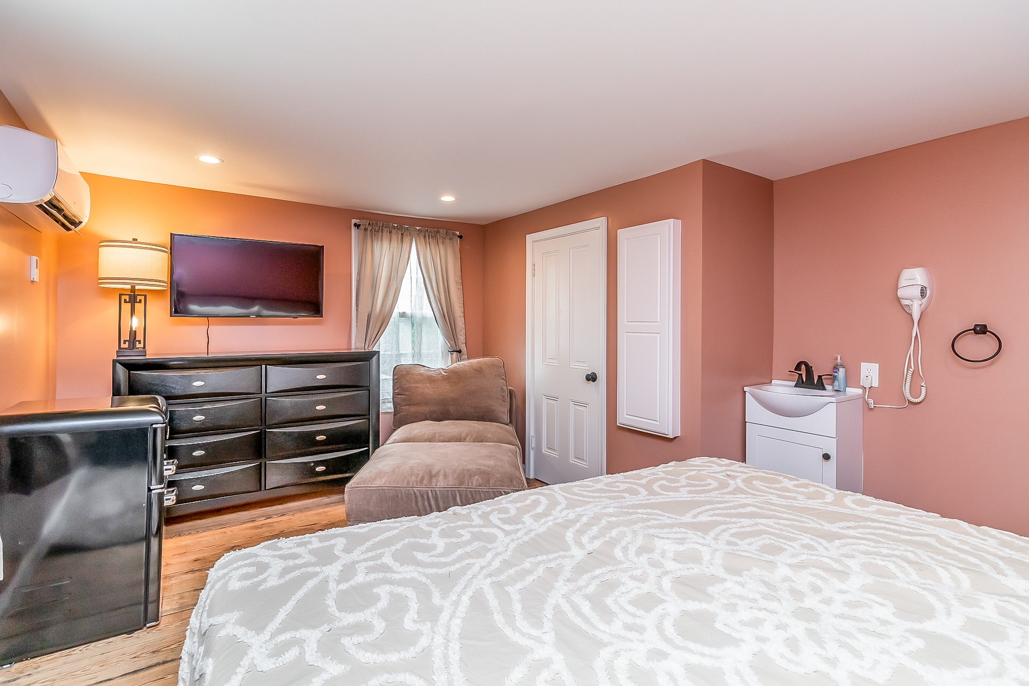 Terracotta bedroom with TV, chaise lounge and in-room vanity sink