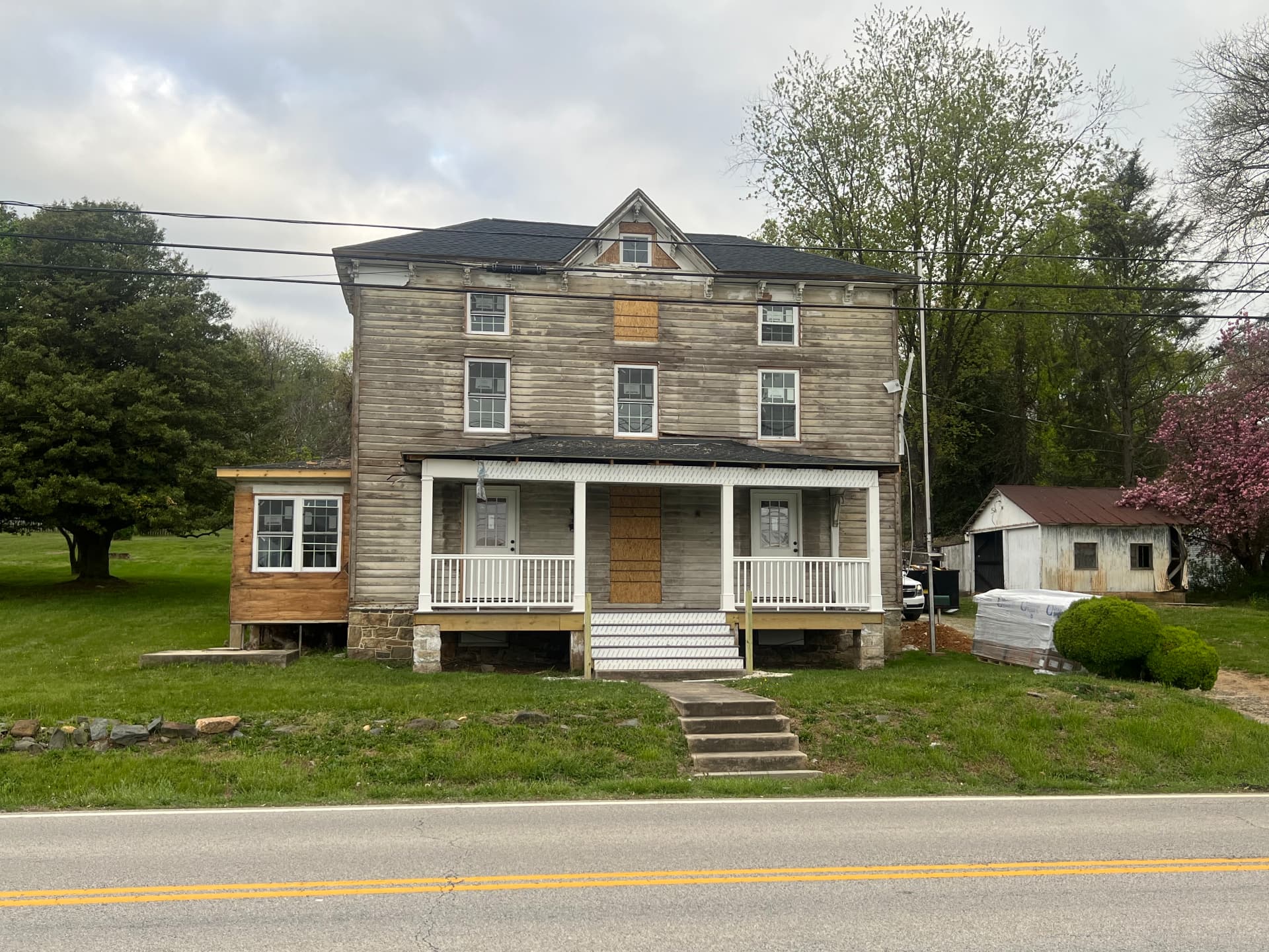 Front of the farmhouse with the rebuilt porch, new steps and siding materials on site