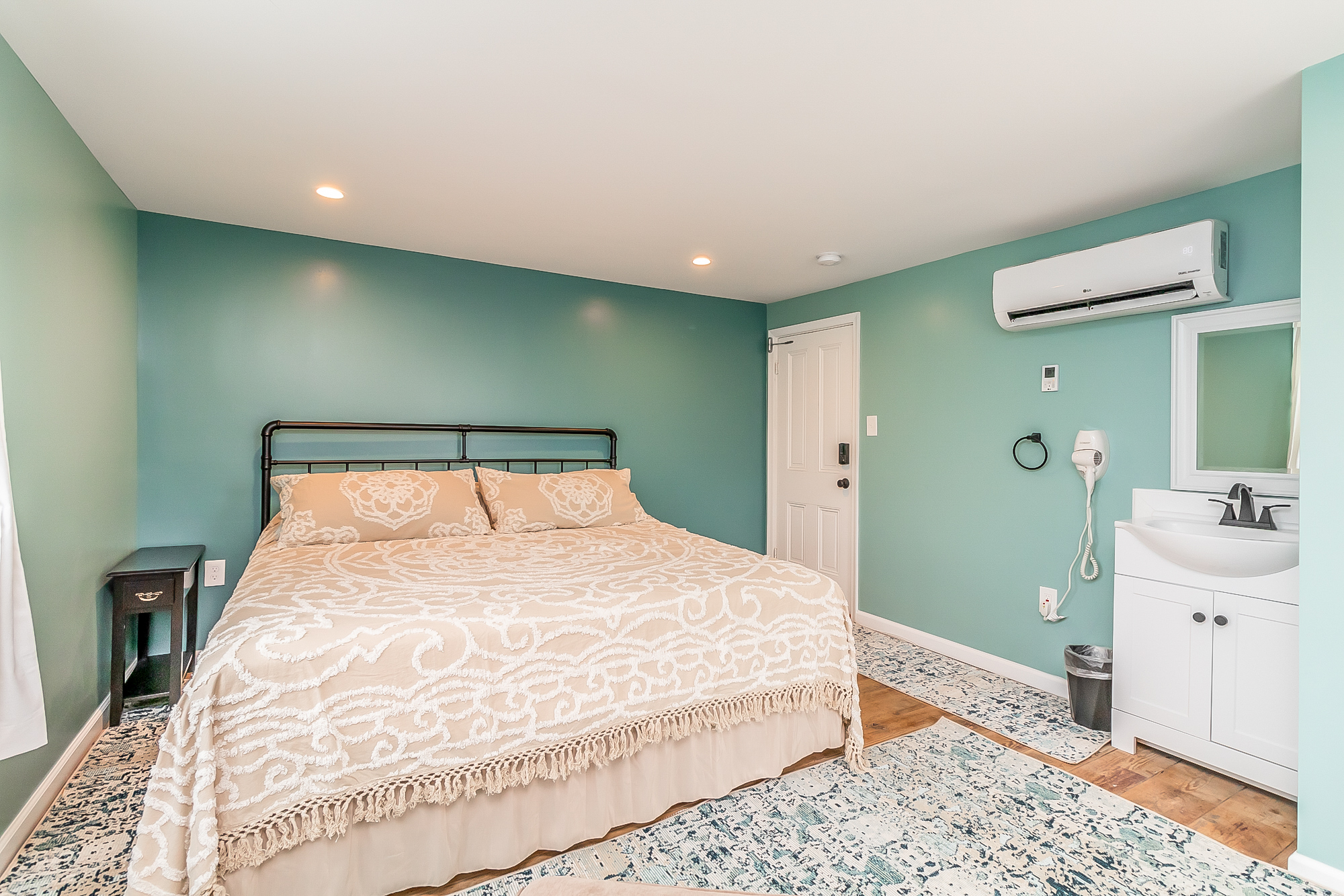 Sea-green bedroom with iron king bed and vanity sink