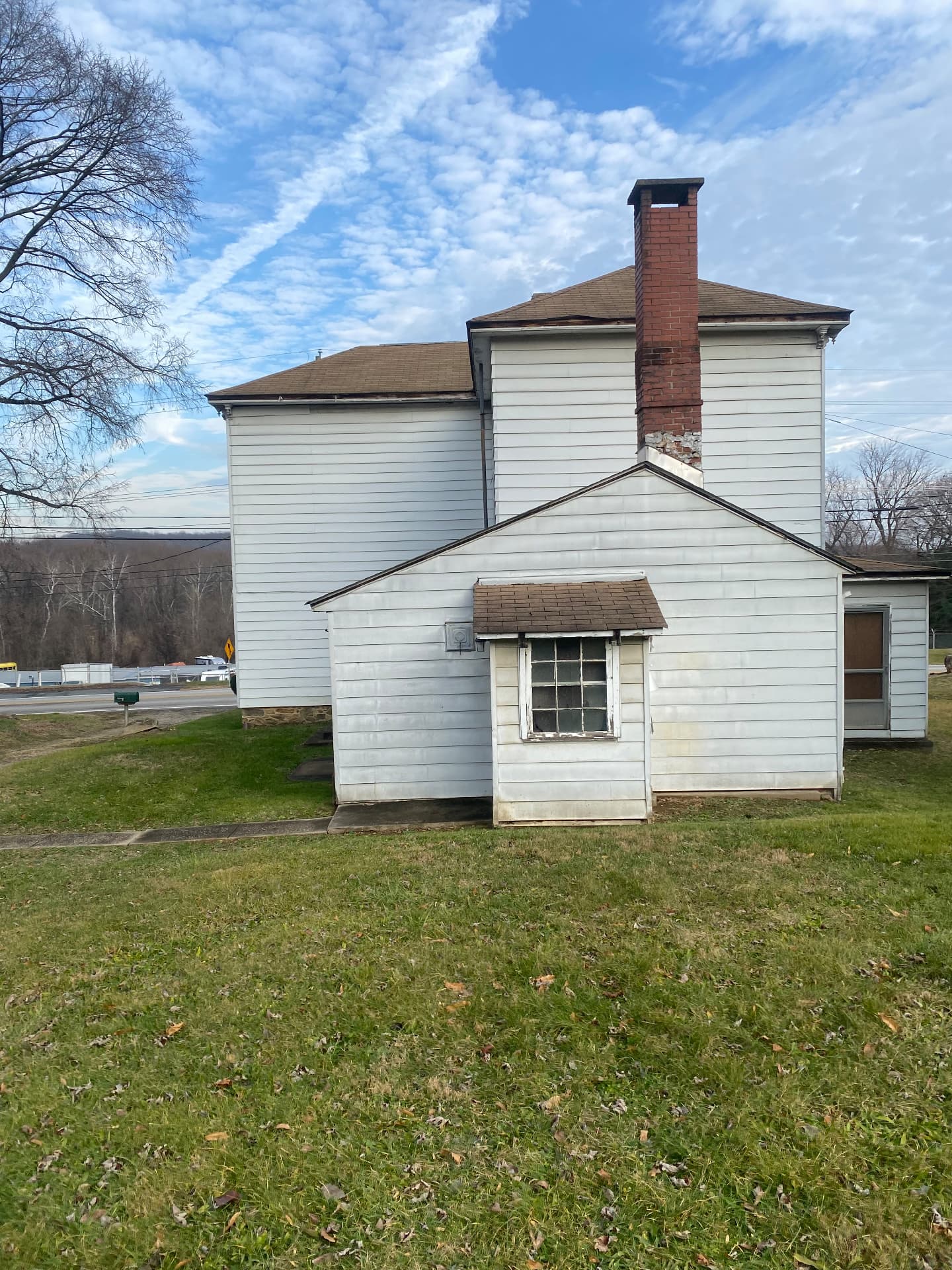 Back of the farmhouse before restoration with a tall brick chimney and low rear additions