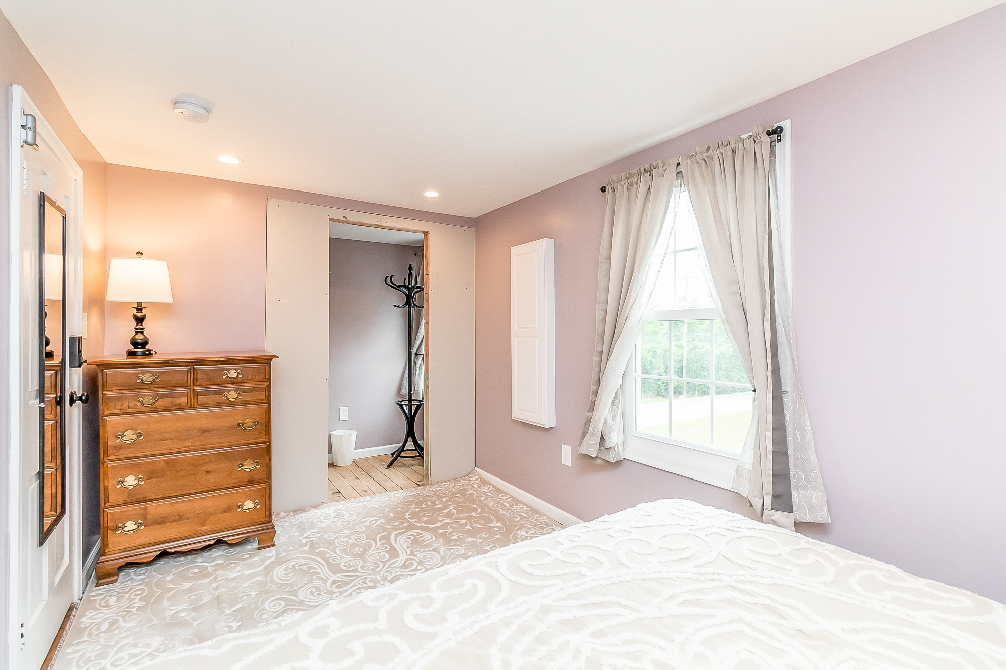 Mauve bedroom with antique dresser, mirror and window seat view