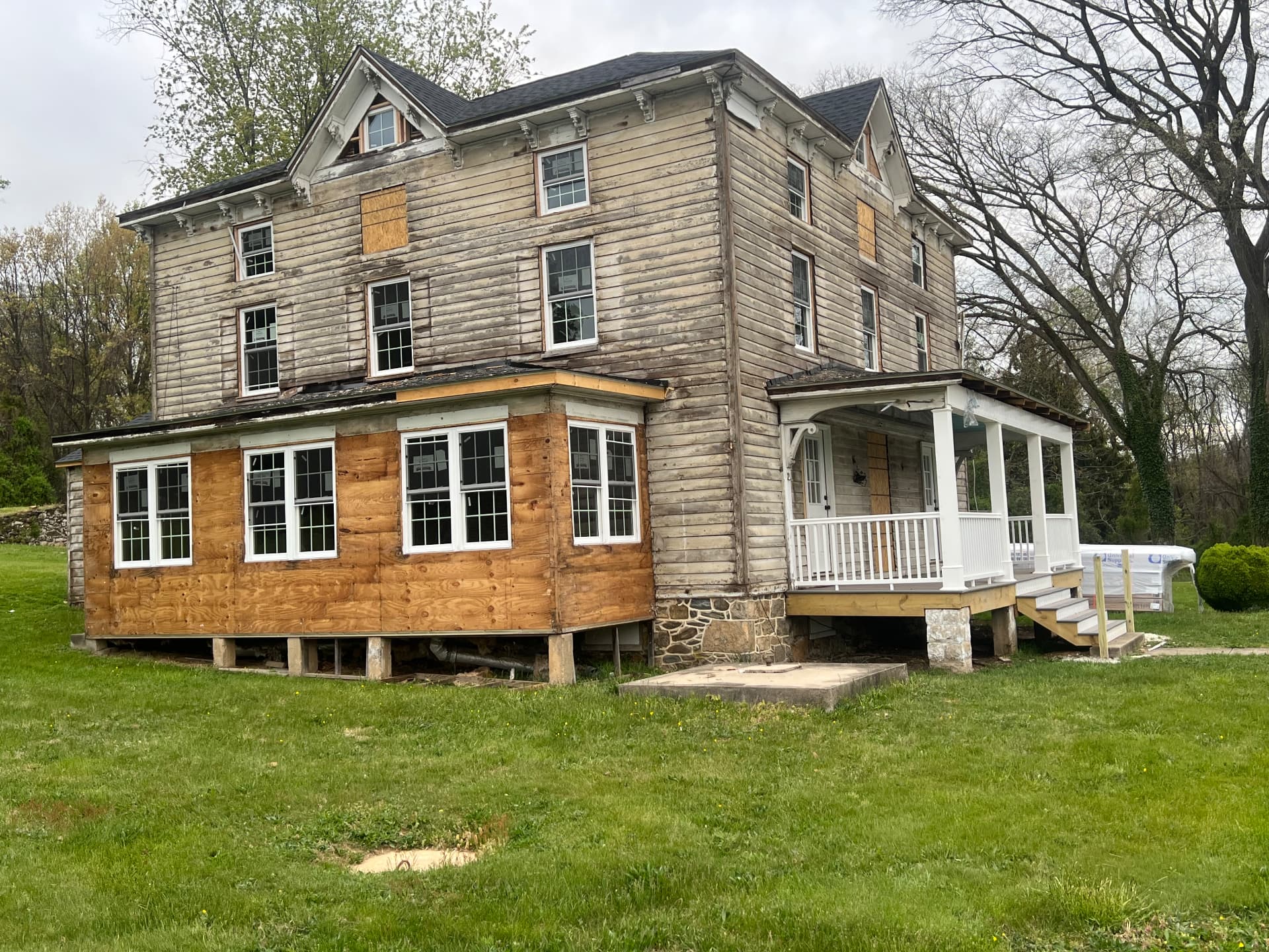 Side of the house stripped to bare wood with the sunroom resheathed and new porch railings in place