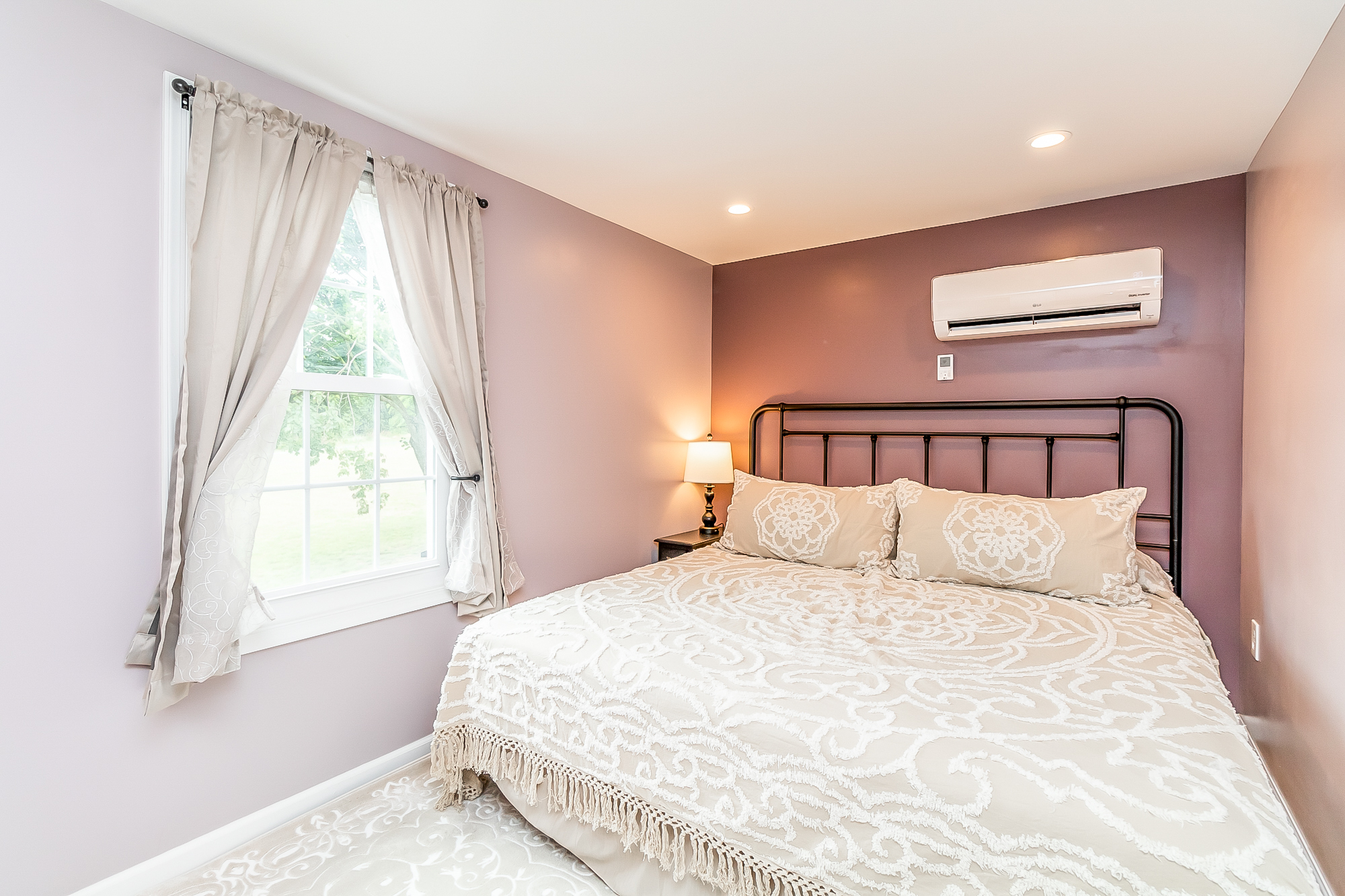 Mauve bedroom with iron bed, chenille coverlet and mini-split