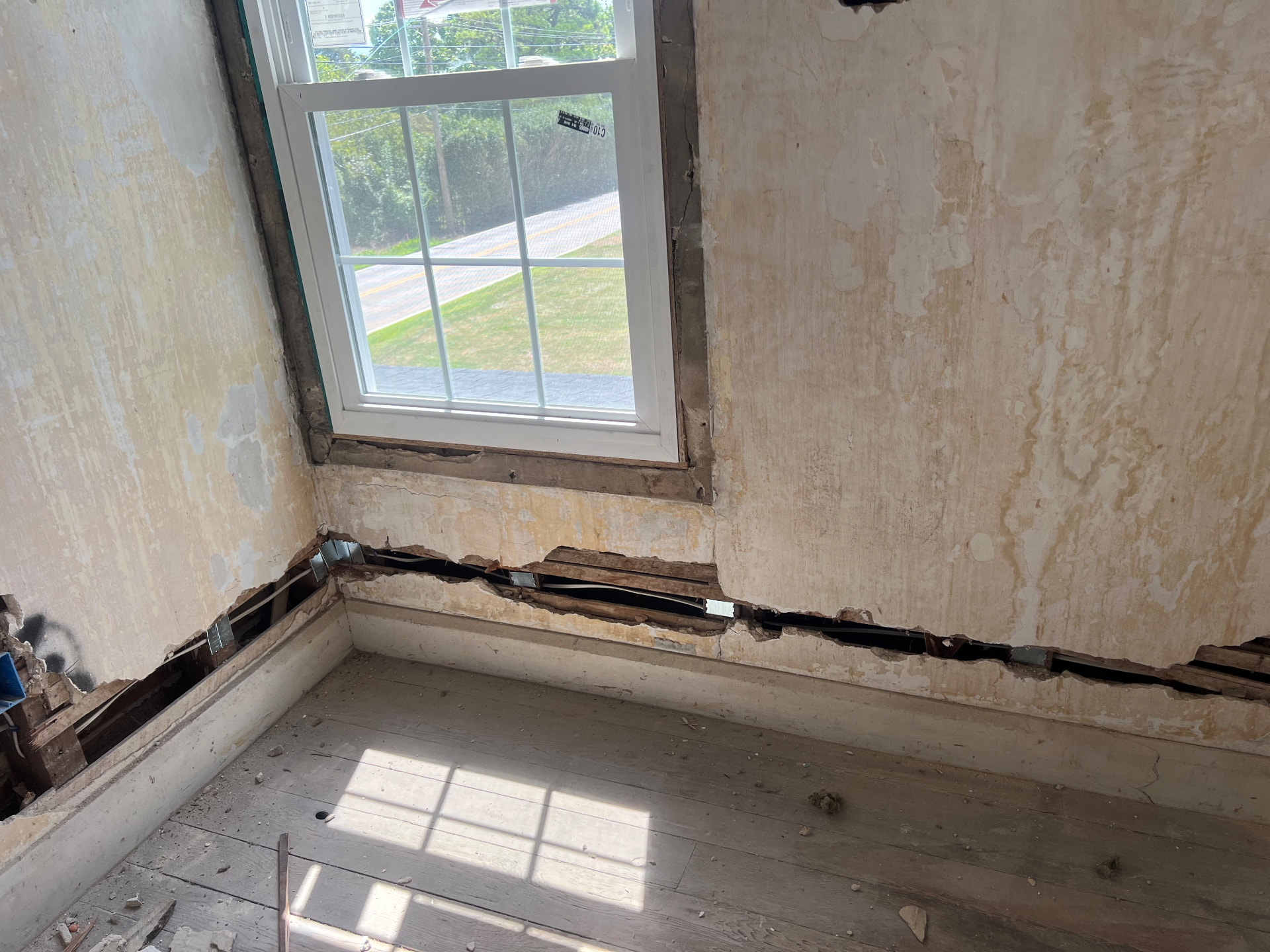 New window set in an original plaster wall opened up along the baseboard for wiring