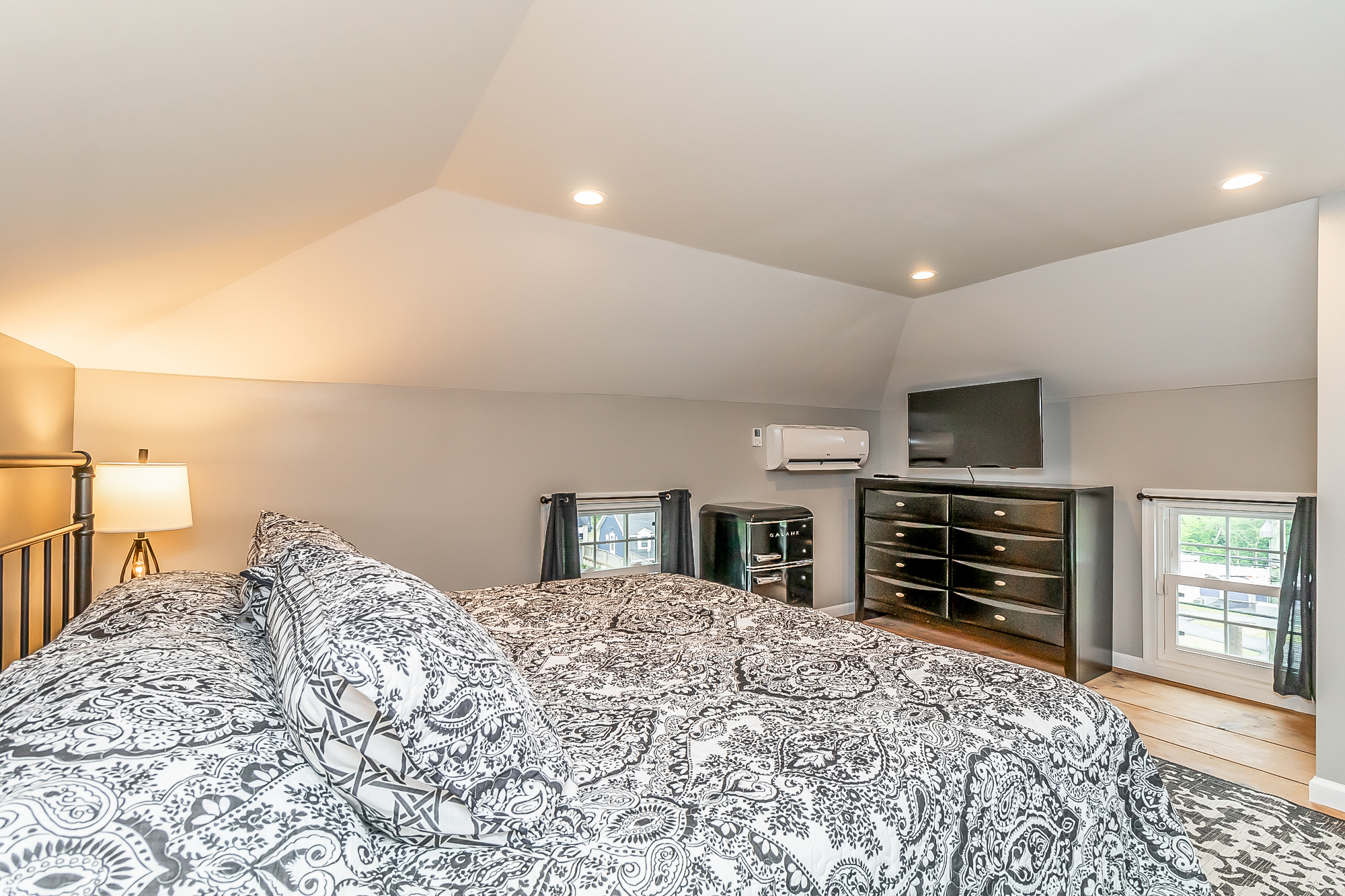King bedroom with TV, dresser, mini fridge and mini-split