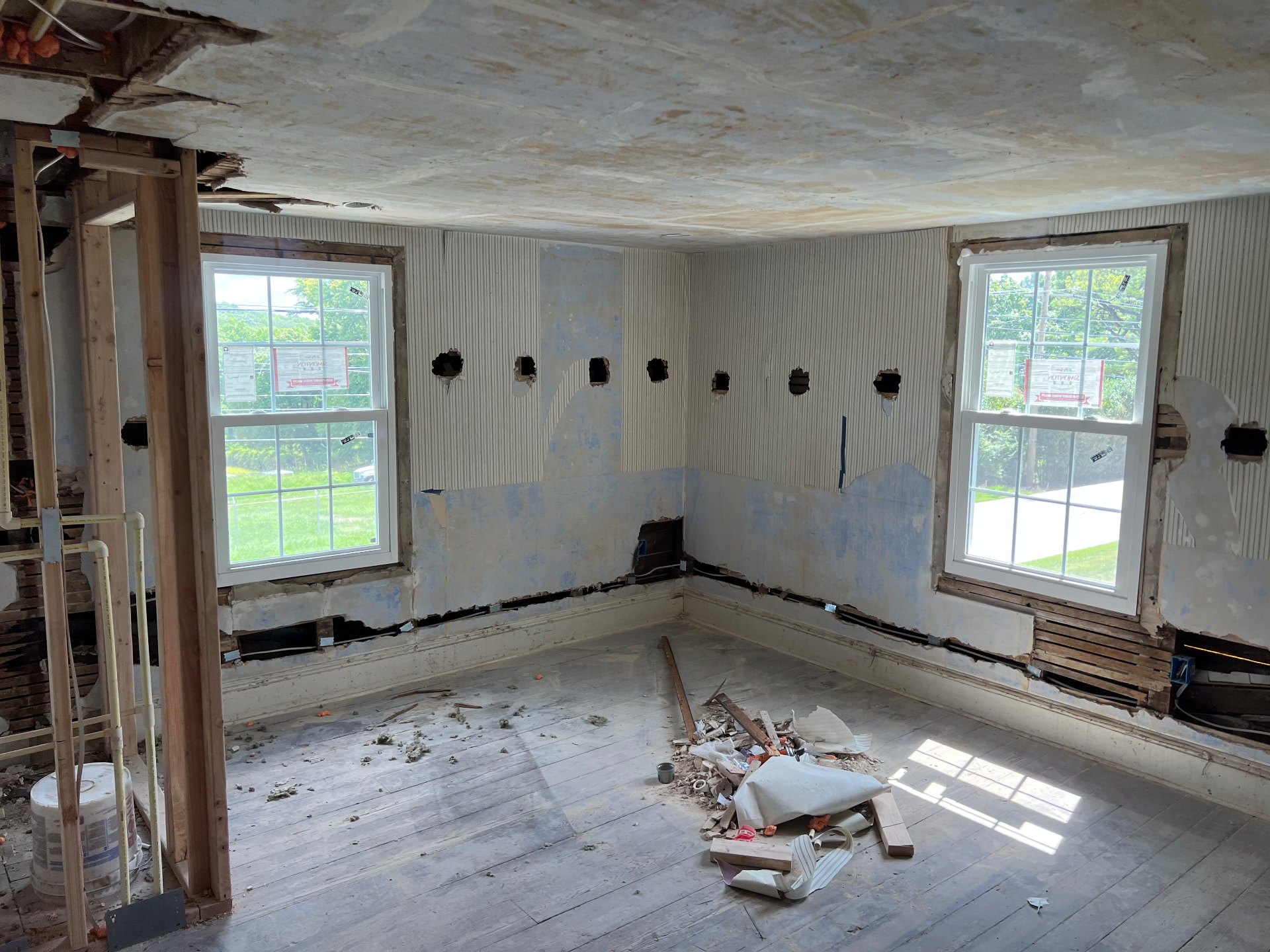 Beadboard walls opened at the baseboards for new wiring between two windows