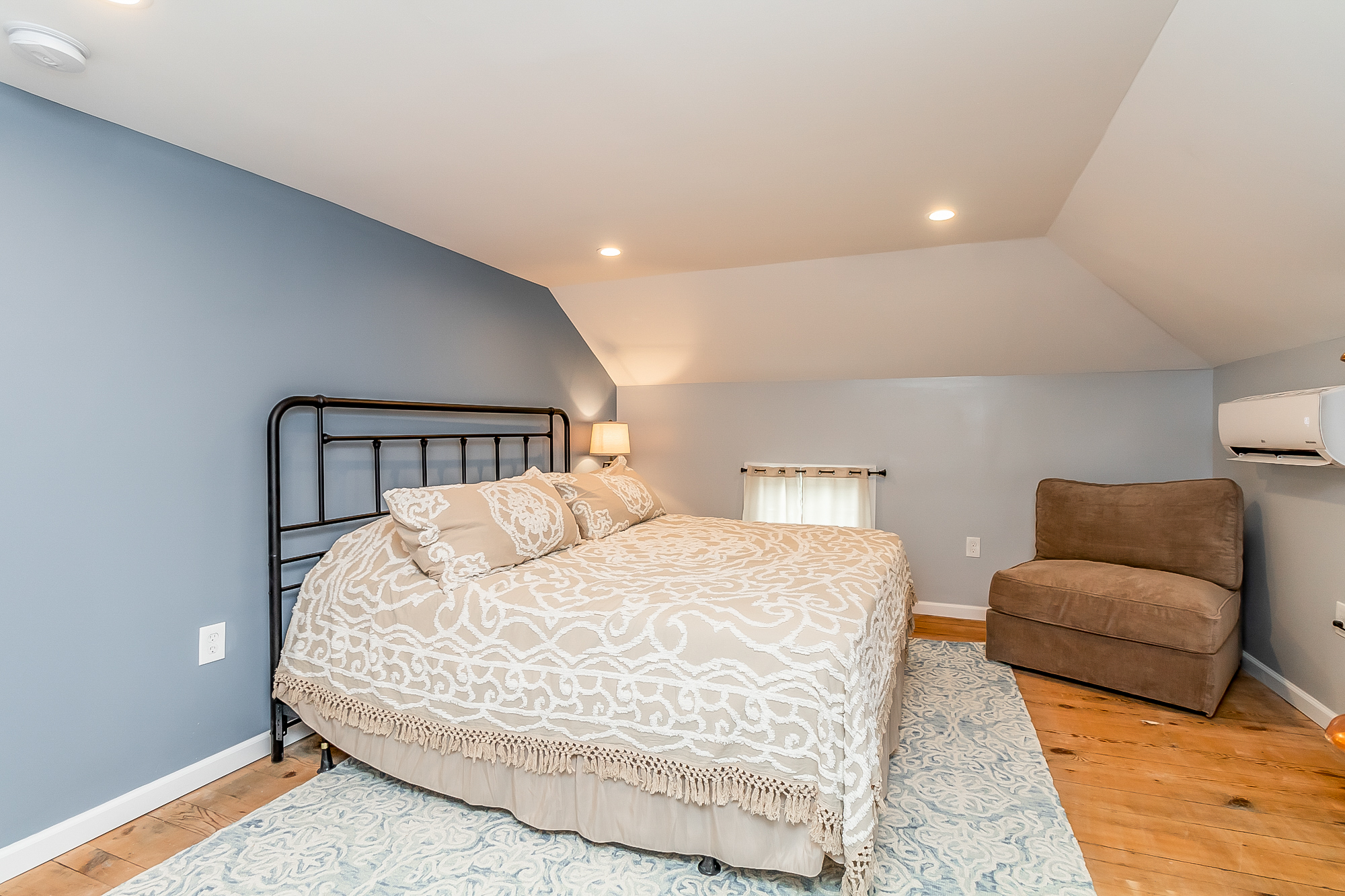 Upstairs bedroom with iron bed, blue walls and restored pine floors