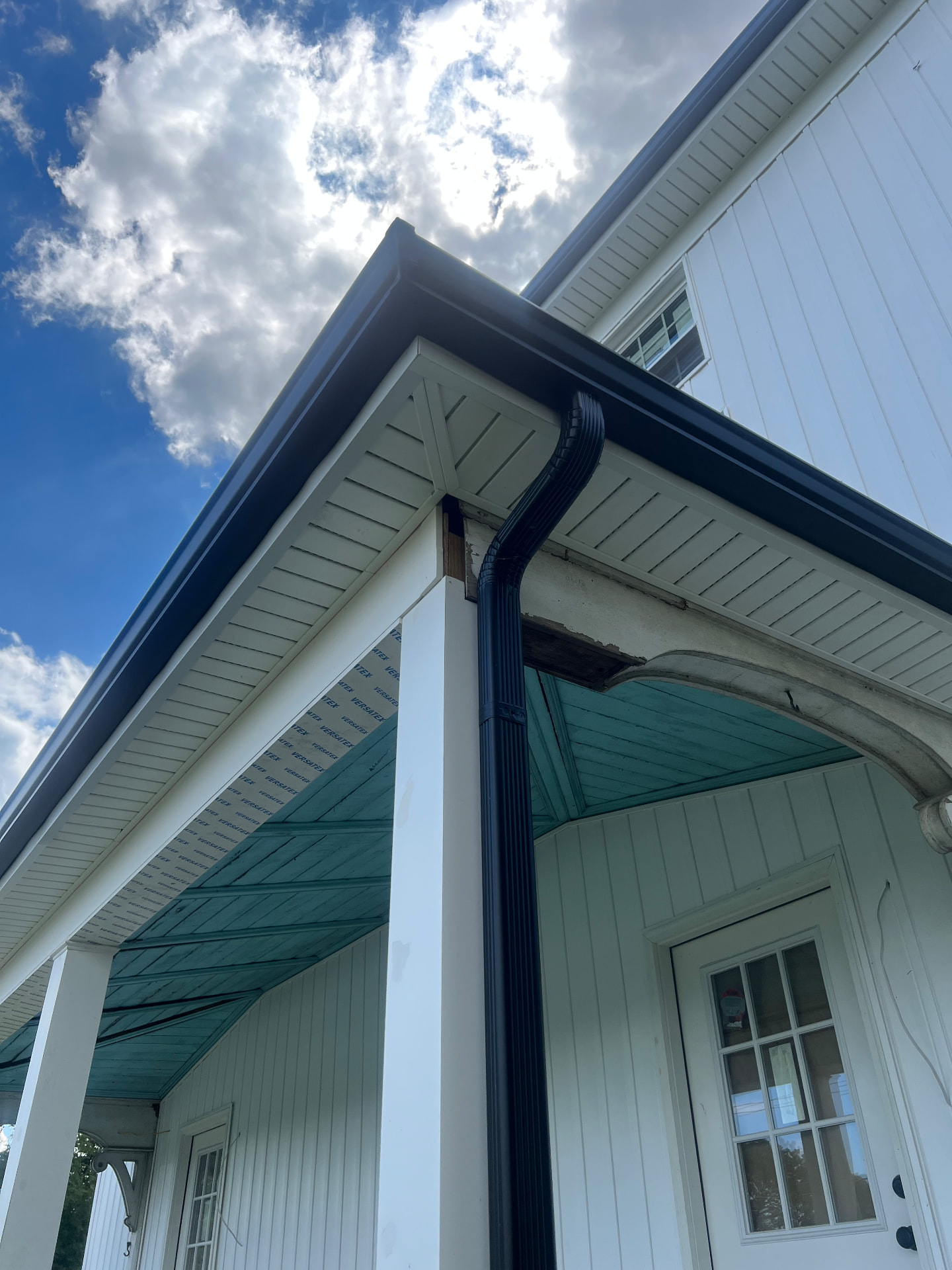 New gutters and downspouts wrapping the finished porch roof