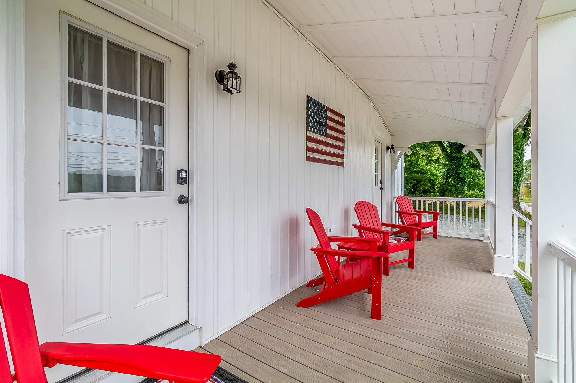 Finished front porch with red Adirondack chairs and keypad entry door