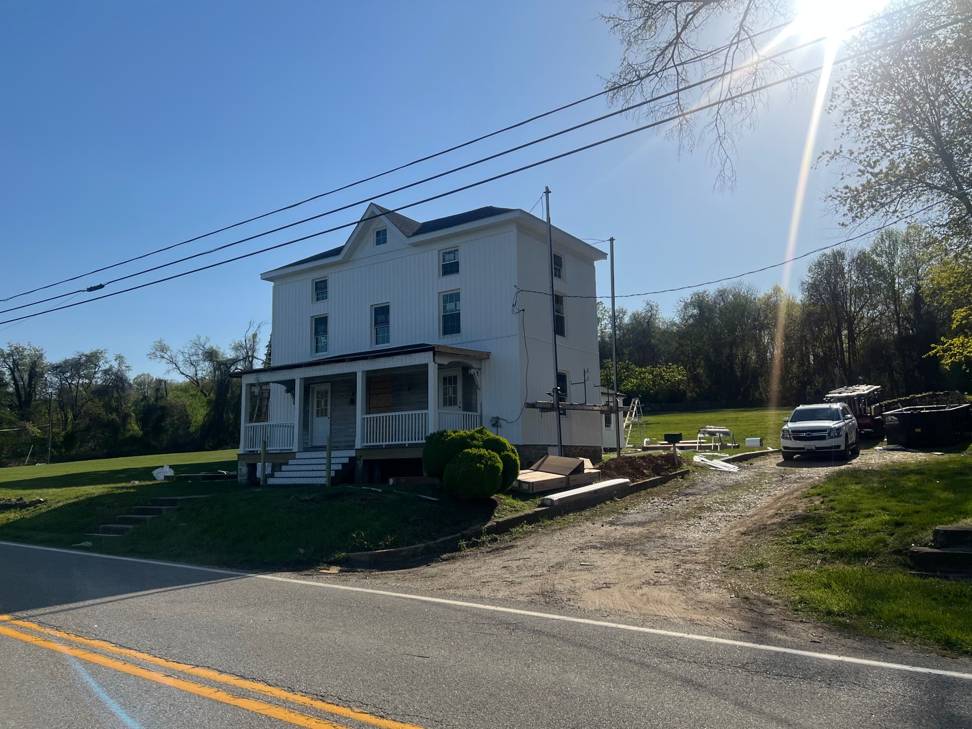 Finished white farmhouse from the road with the rebuilt porch and new steps