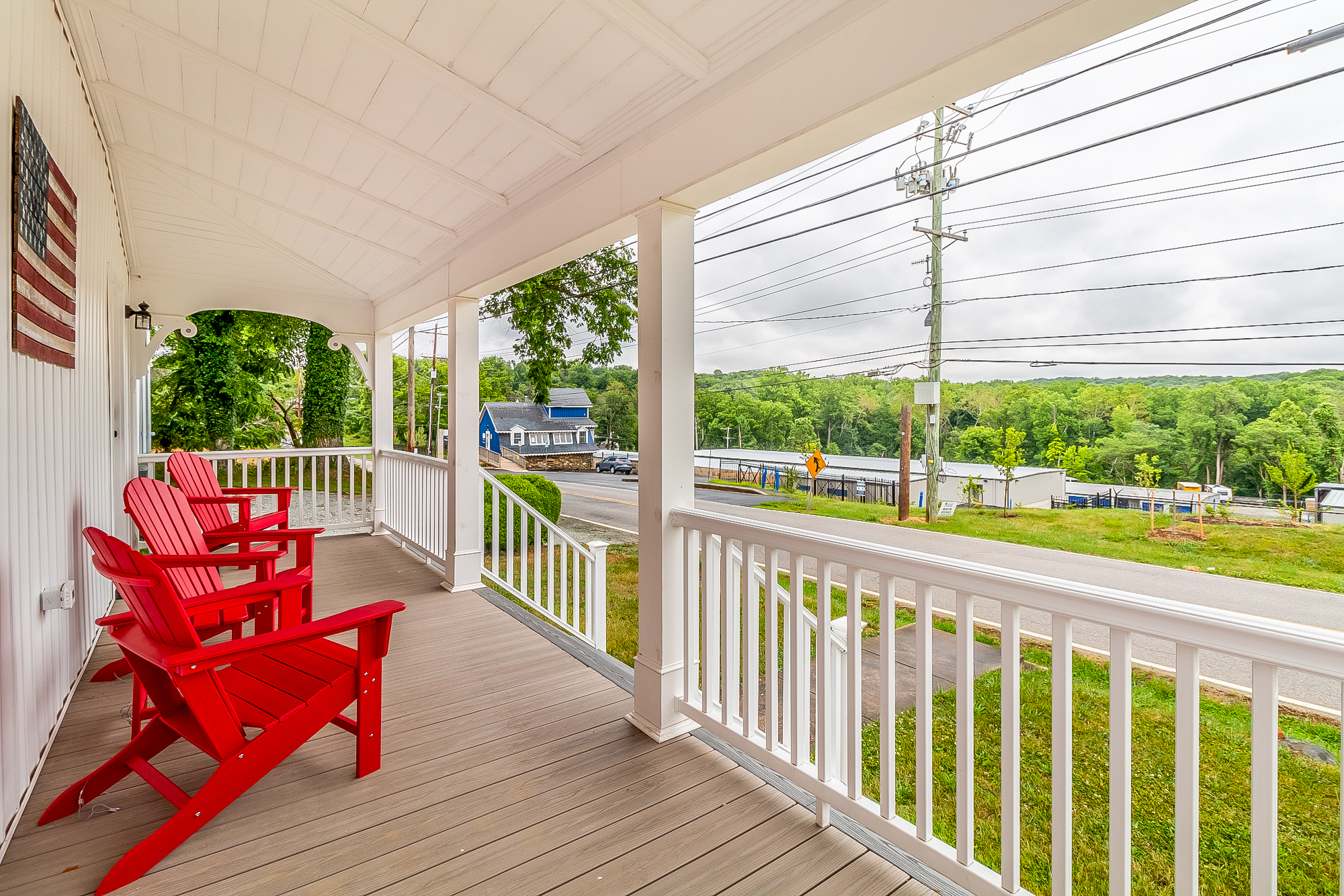 Red porch chairs under the restored beadboard ceiling with a country view