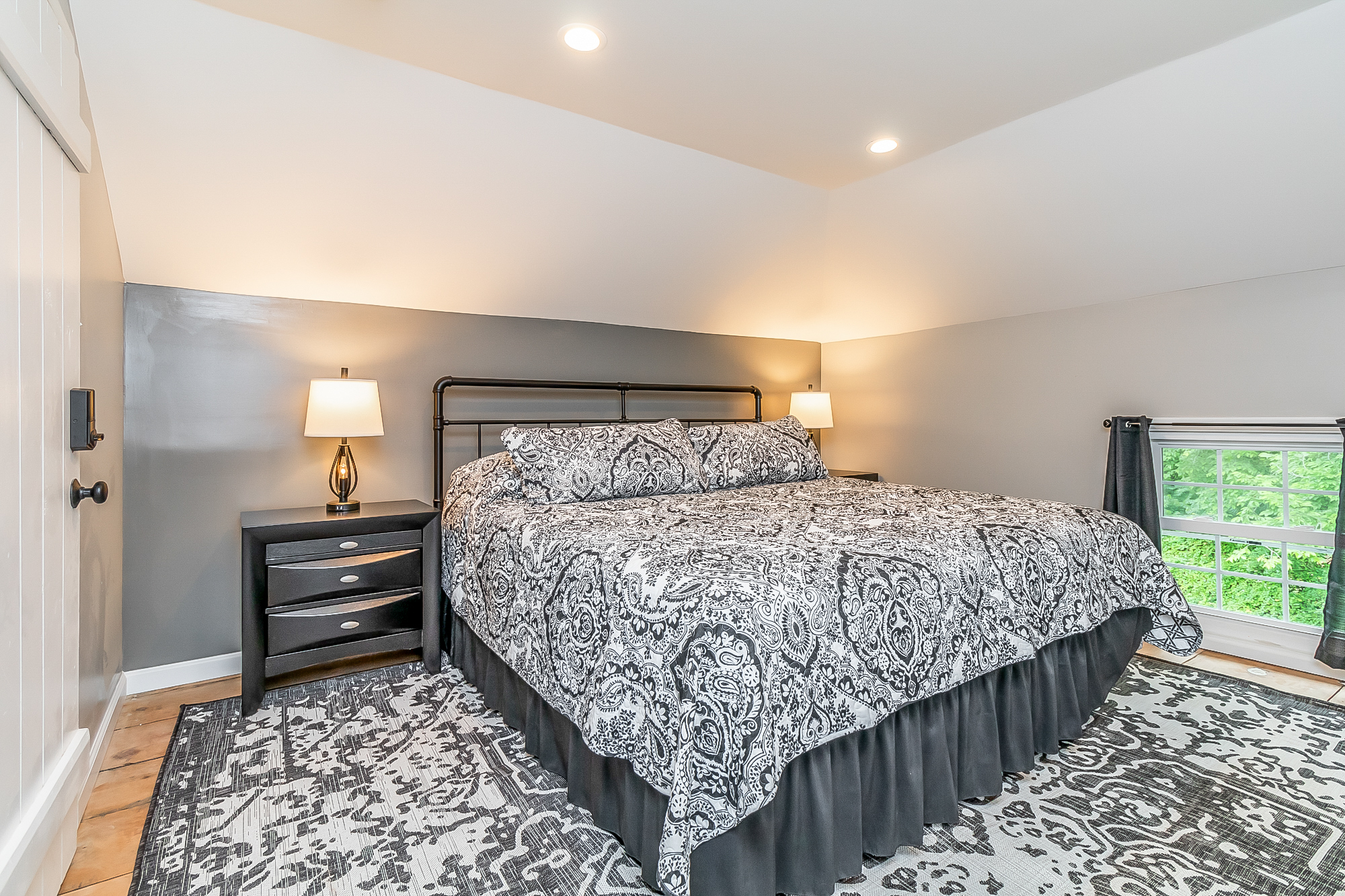 Bedroom with iron king bed, paisley bedding and garden view window