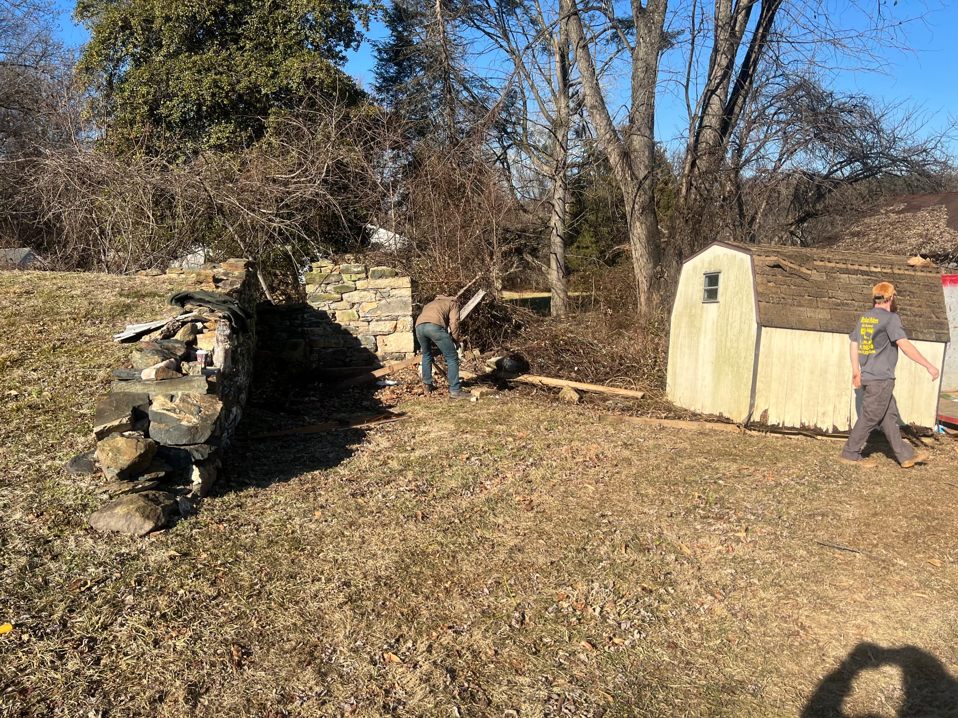 Crew clearing brush away from the old stone walls behind the house