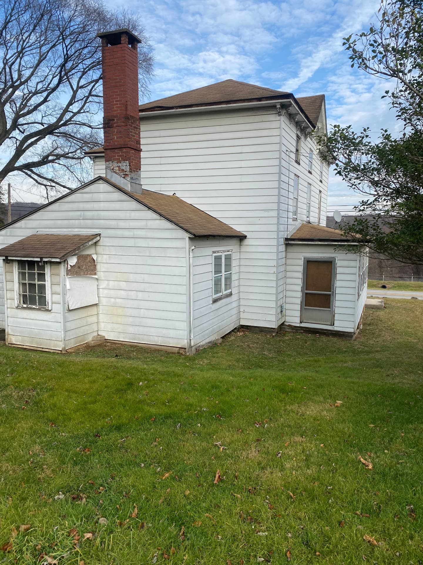 Rear additions before restoration showing damaged siding and a boarded door