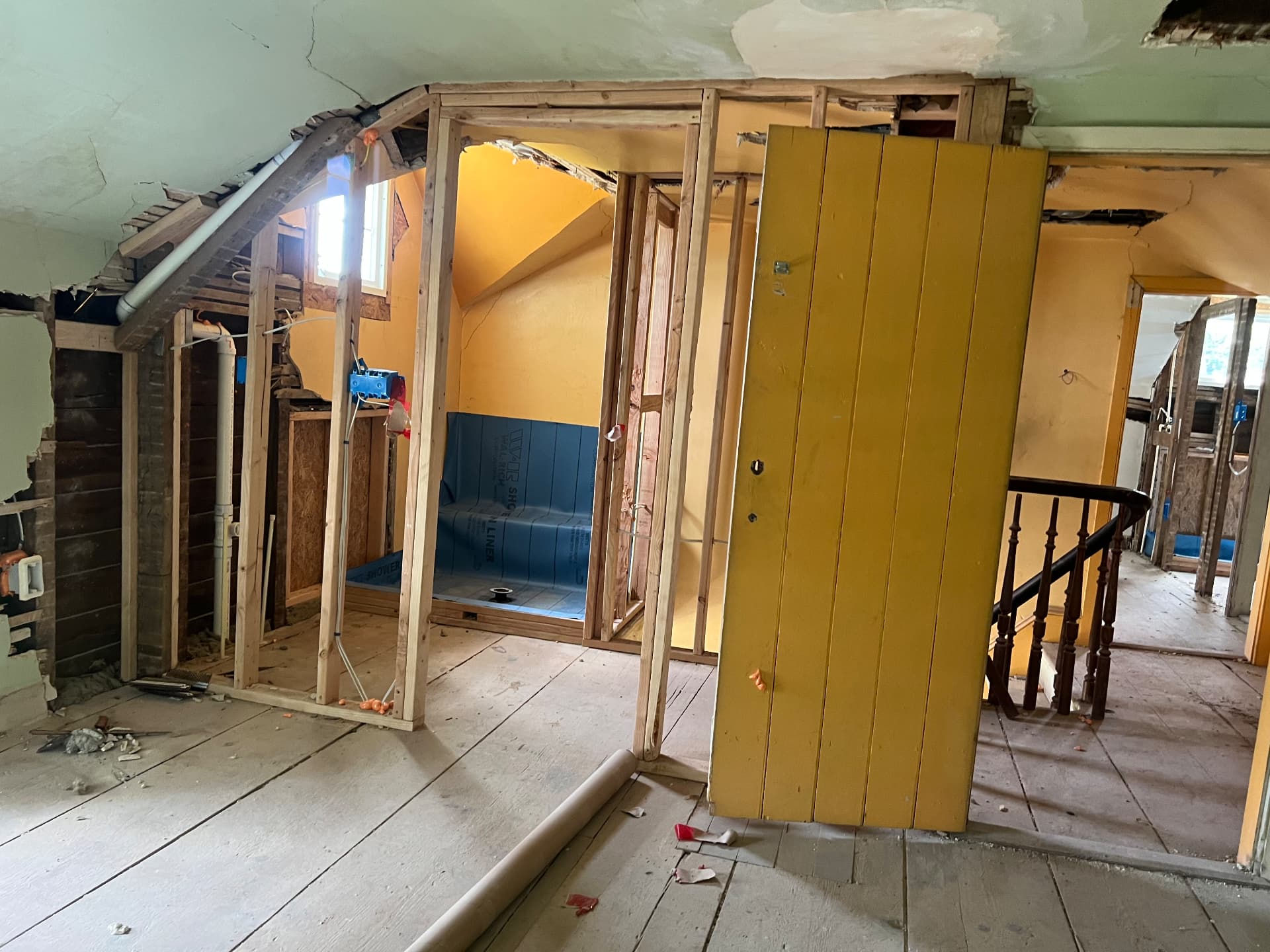 Original plank door set aside while the new bathroom is framed and lined