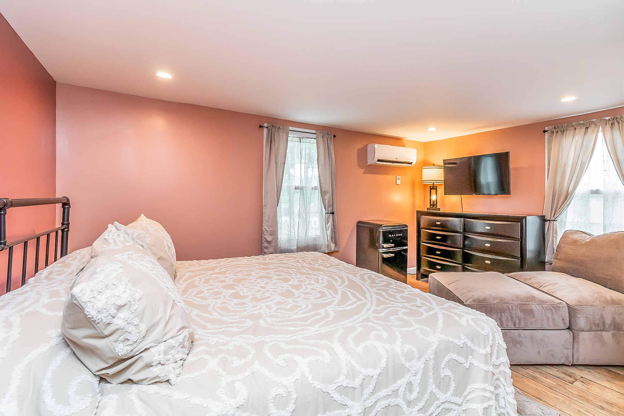Warm terracotta bedroom with king bed, TV, mini fridge and lounge seating
