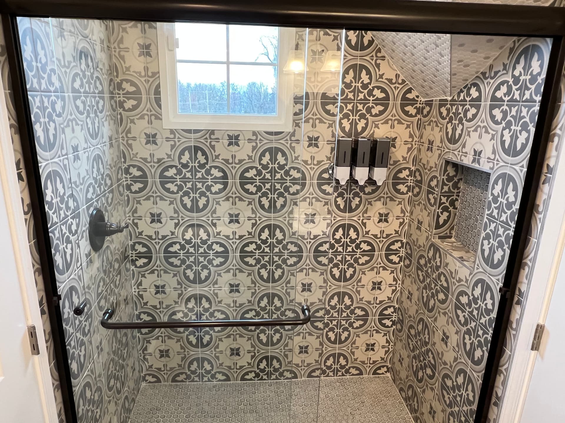 New tiled walk-in shower with patterned tile and glass doors