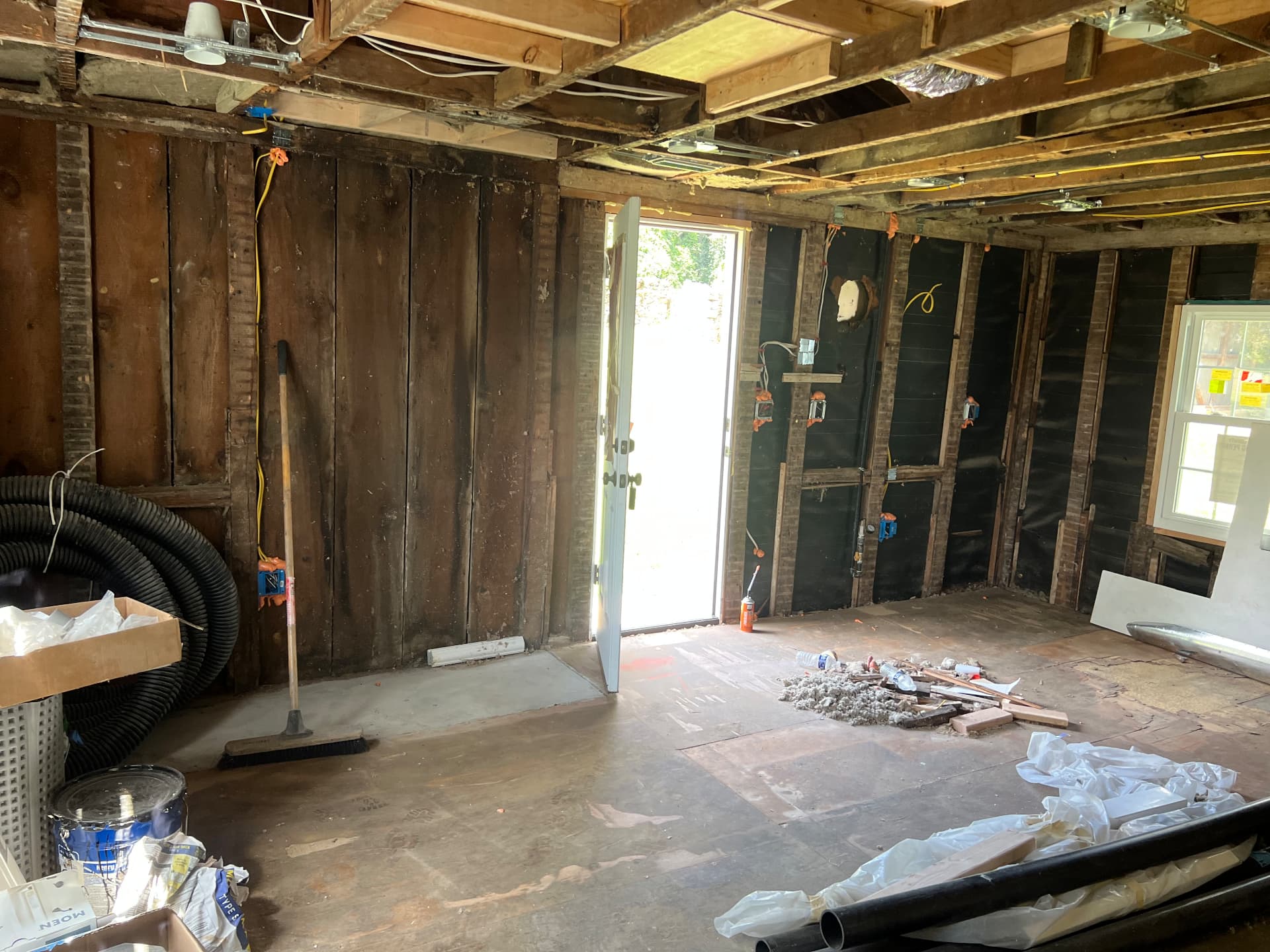 Rear room stripped to plank walls and new sheathing with a new exterior door set in