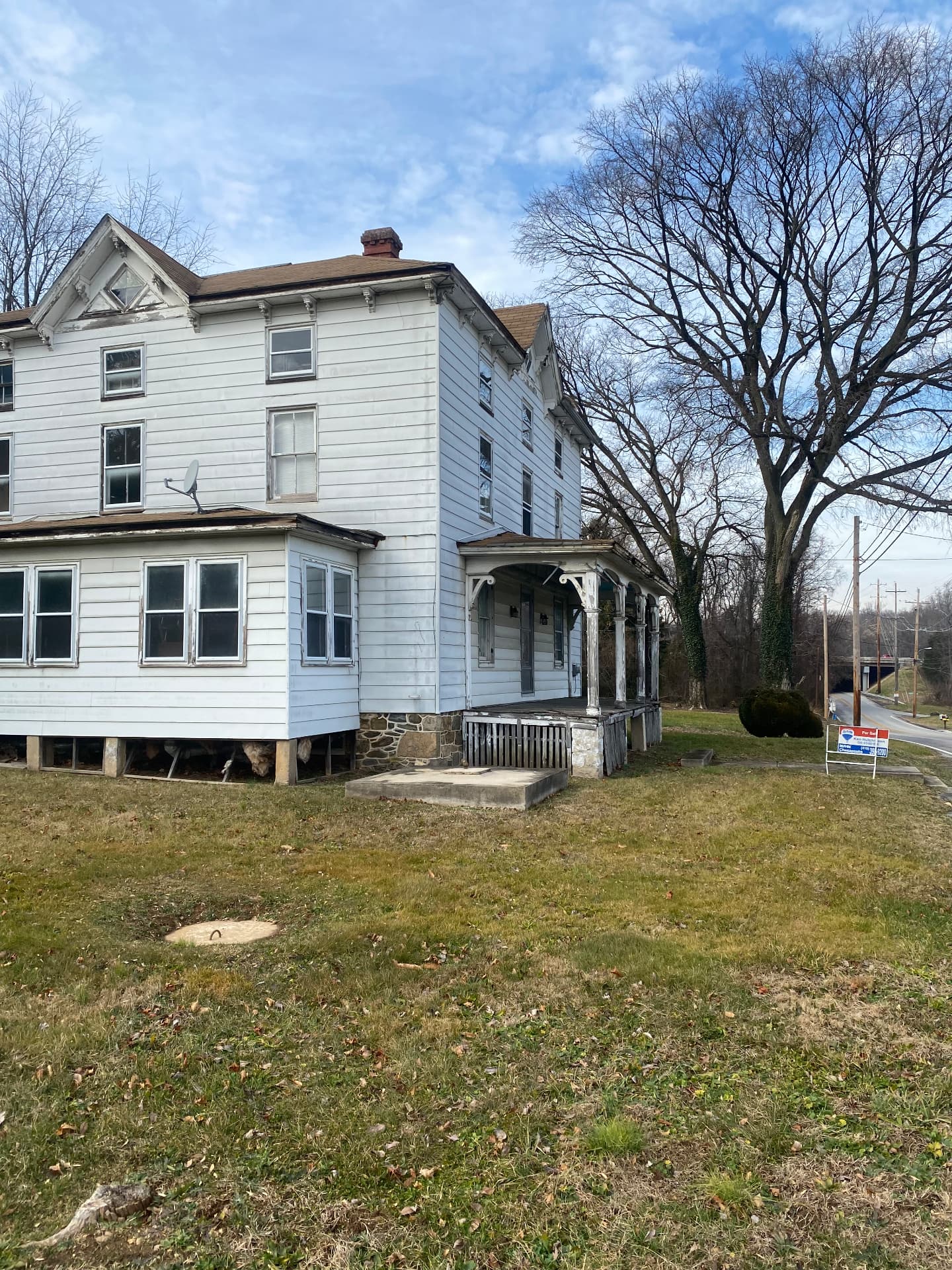 Side elevation of the farmhouse before restoration showing peeling paint and a sagging porch