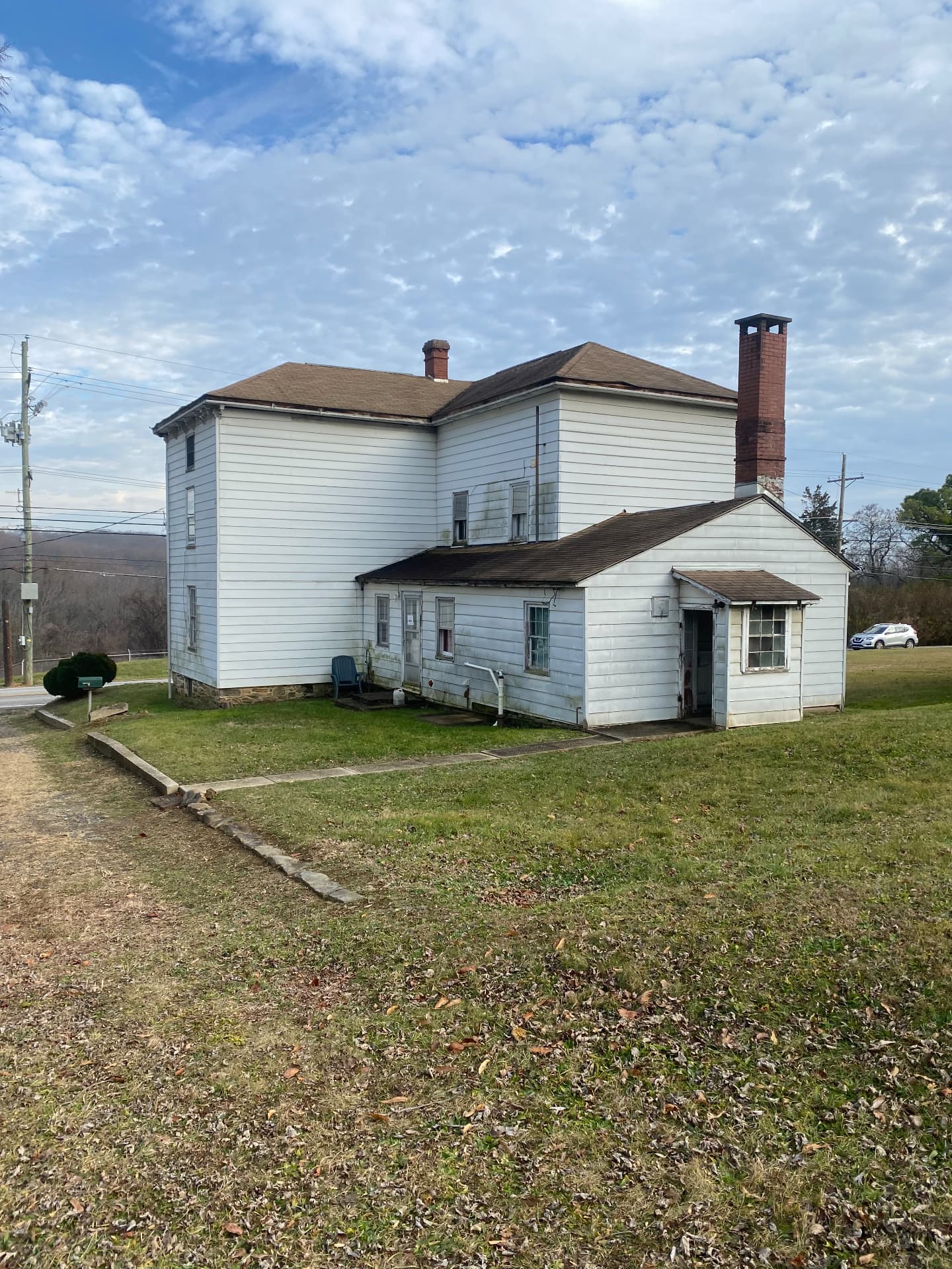 Rear of the farmhouse before restoration with stained siding and an aging brick chimney