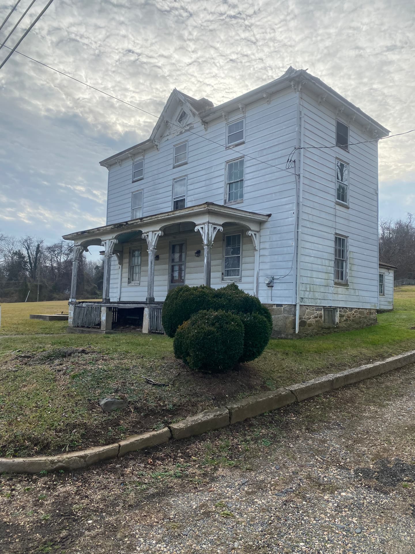 The farmhouse before restoration with failing porch piers and overgrown yard