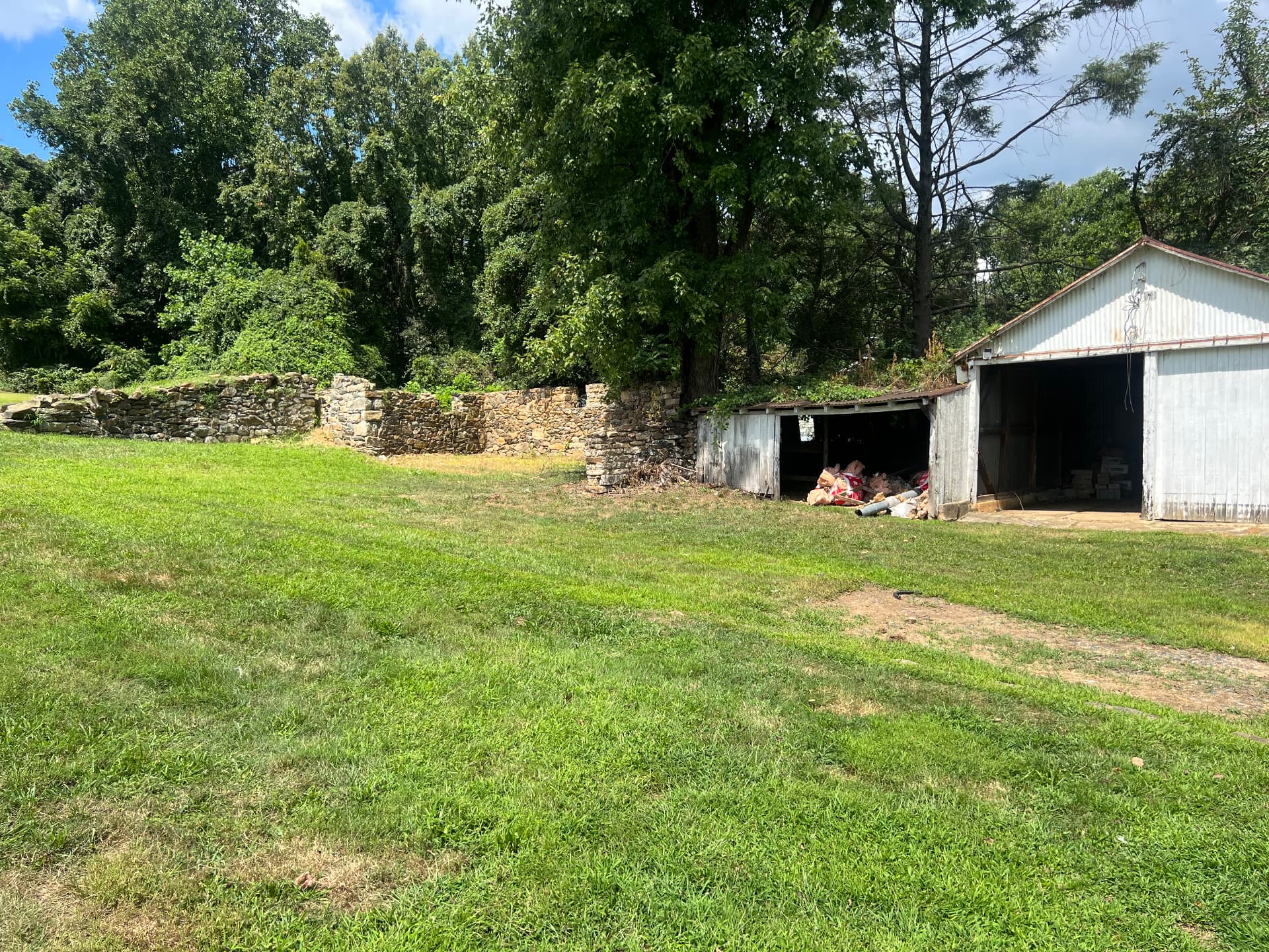 Old barn and shed beside the original dry-stacked stone walls before the grounds were cleared