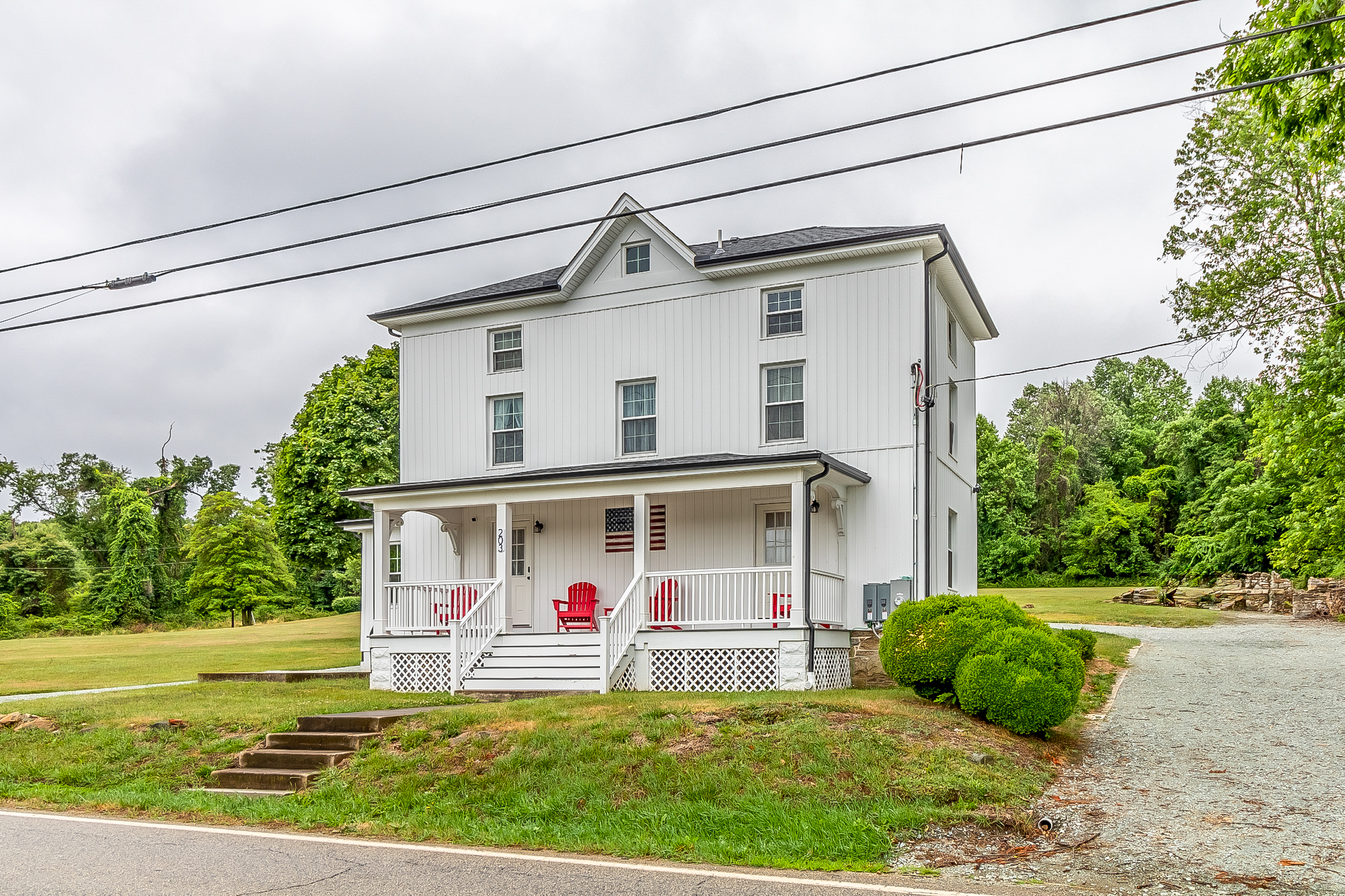 Front corner of the restored farmhouse with new siding, roof and porch railings