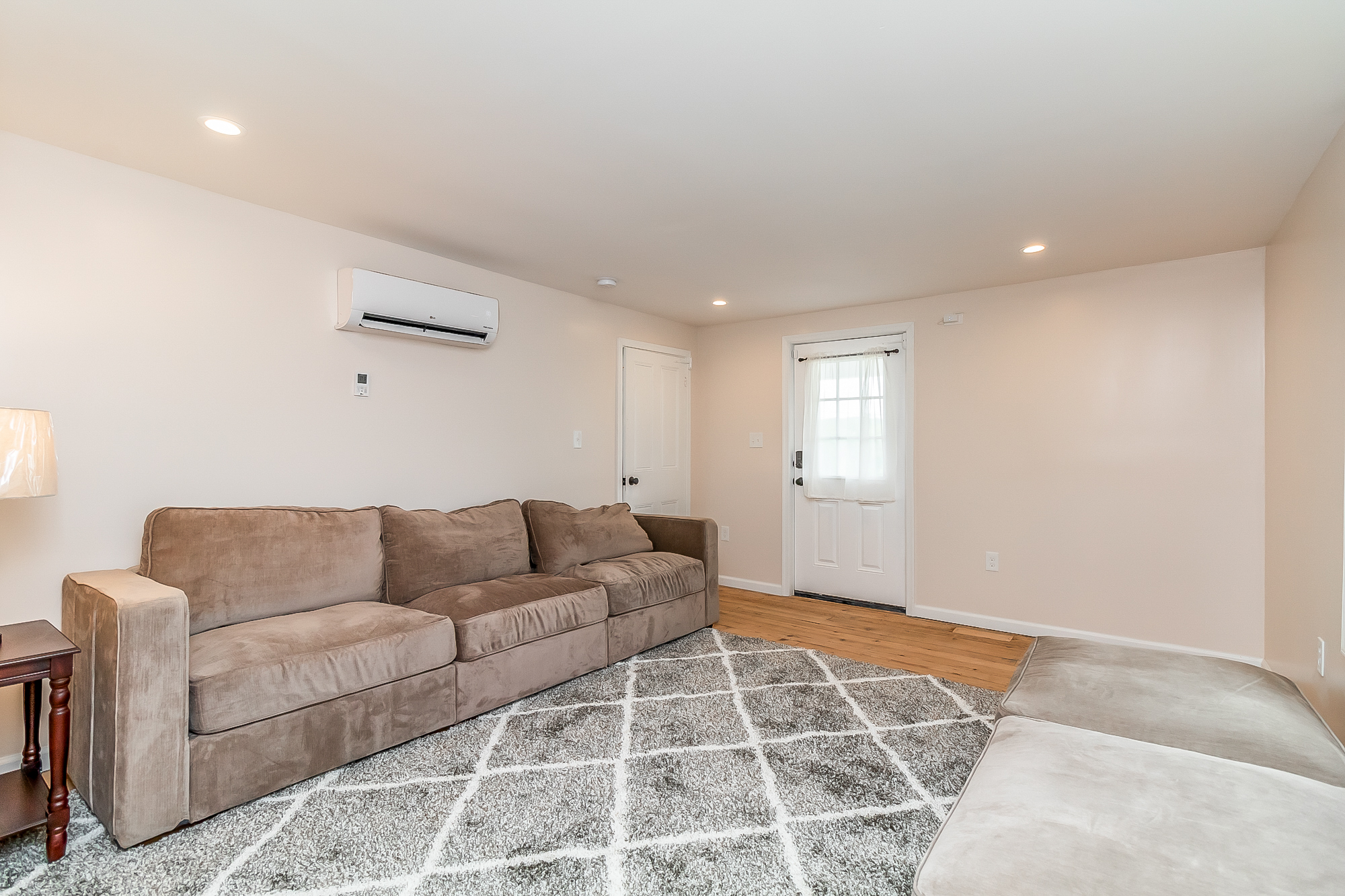 Finished family room with long sofas, new flooring and mini-split heating and cooling