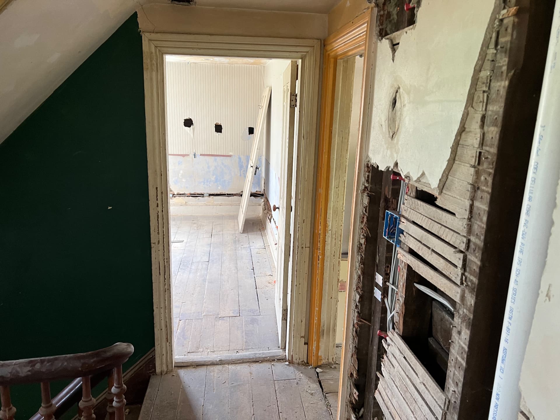 Upstairs hall with original doors and trim kept in place while walls are rewired